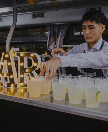 Host serves cocktails at the bus bar