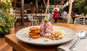 Plato de ceviche peruano clásico con trozos de pescado blanco, cebolla roja, camote, choclo y cancha serrana en un restaurante de Lima.